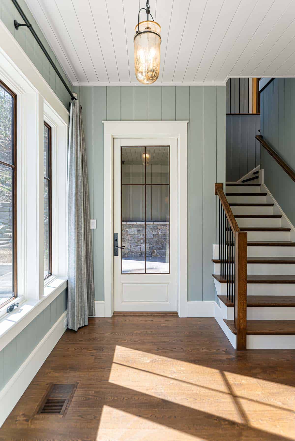 Mudroom with green paneled walls and staircase view