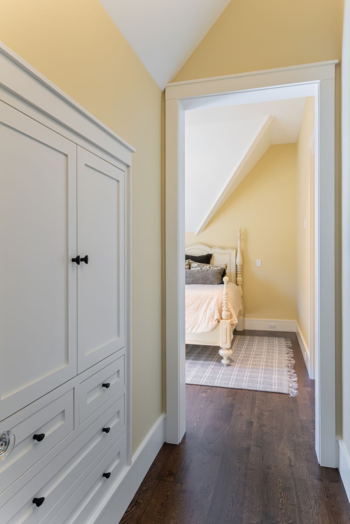Hallway with white armoire and view into yellow bedroom