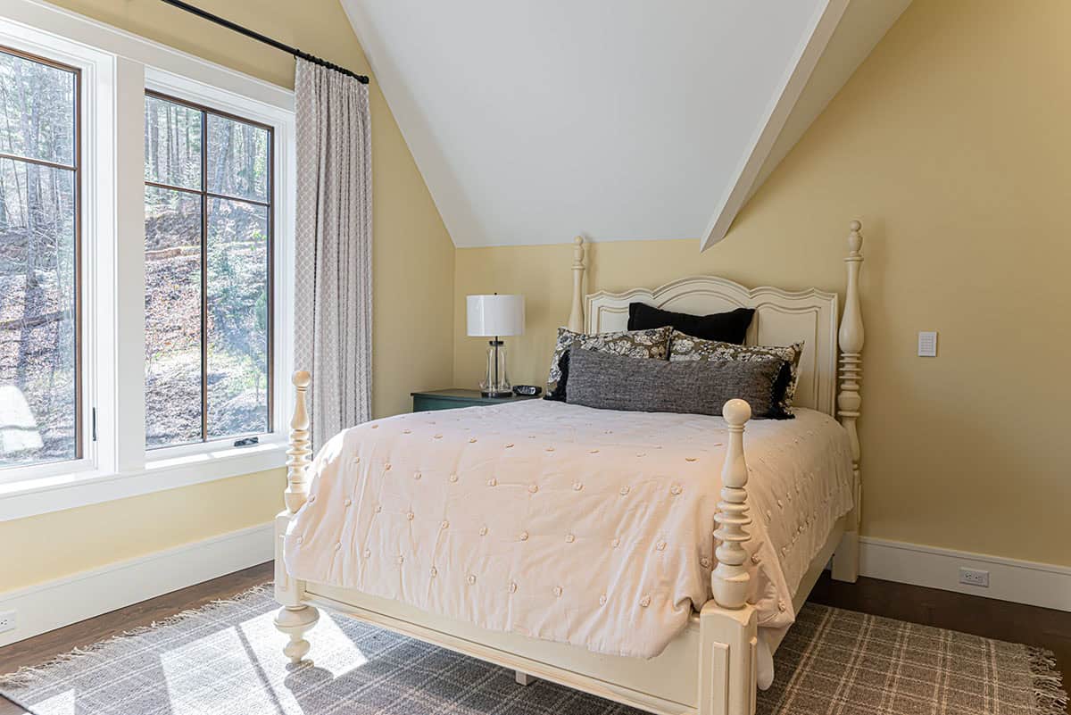 Guest bedroom with cream four-poster bed and yellow walls