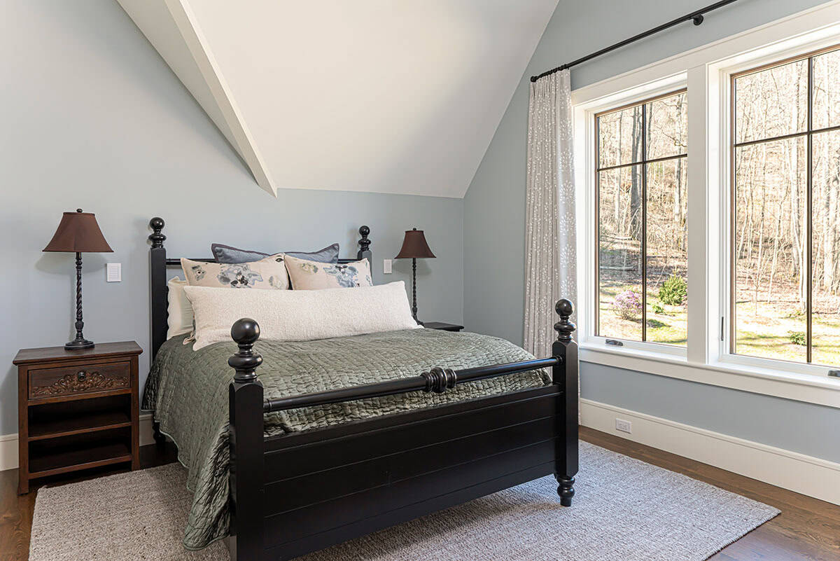 Guest bedroom with black four-poster bed and forest view
