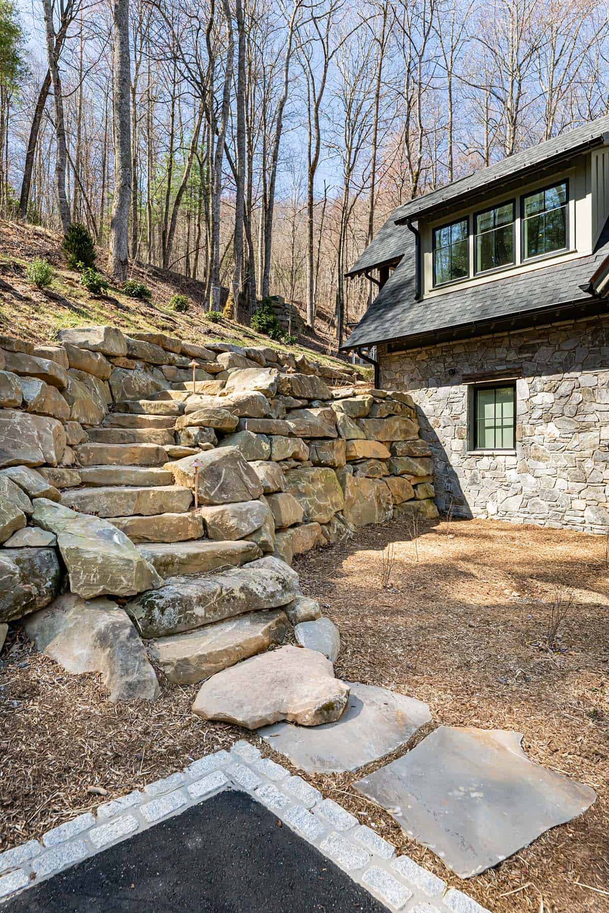 Stone retaining wall steps leading up wooded hillside