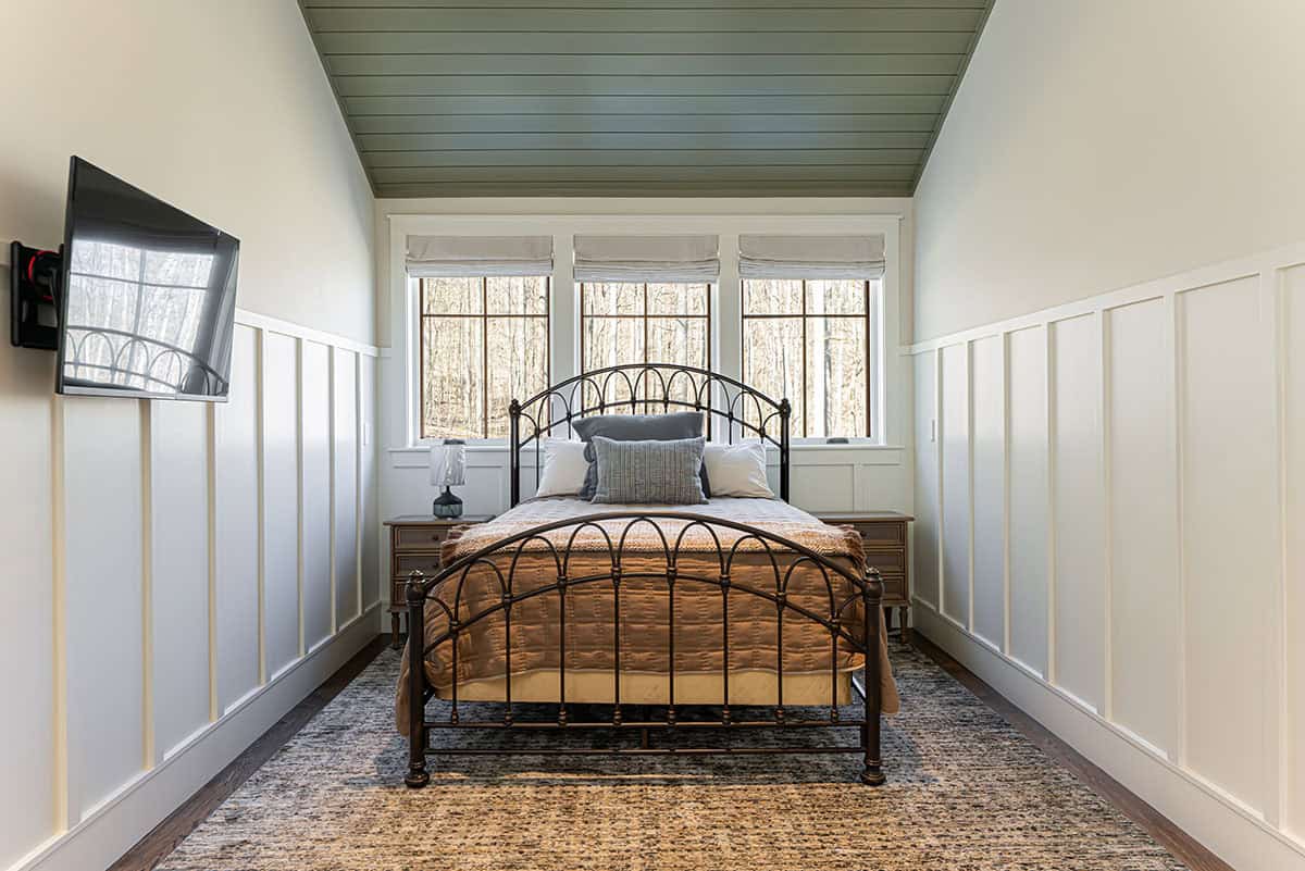 Guest suite bedroom with arched iron bed and board and batten walls