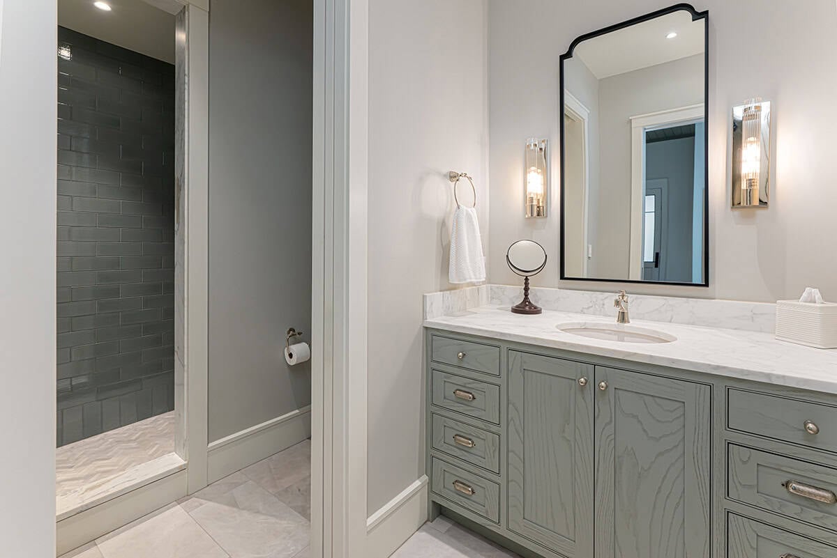 Bathroom vanity with sage cabinets and walk-in shower view
