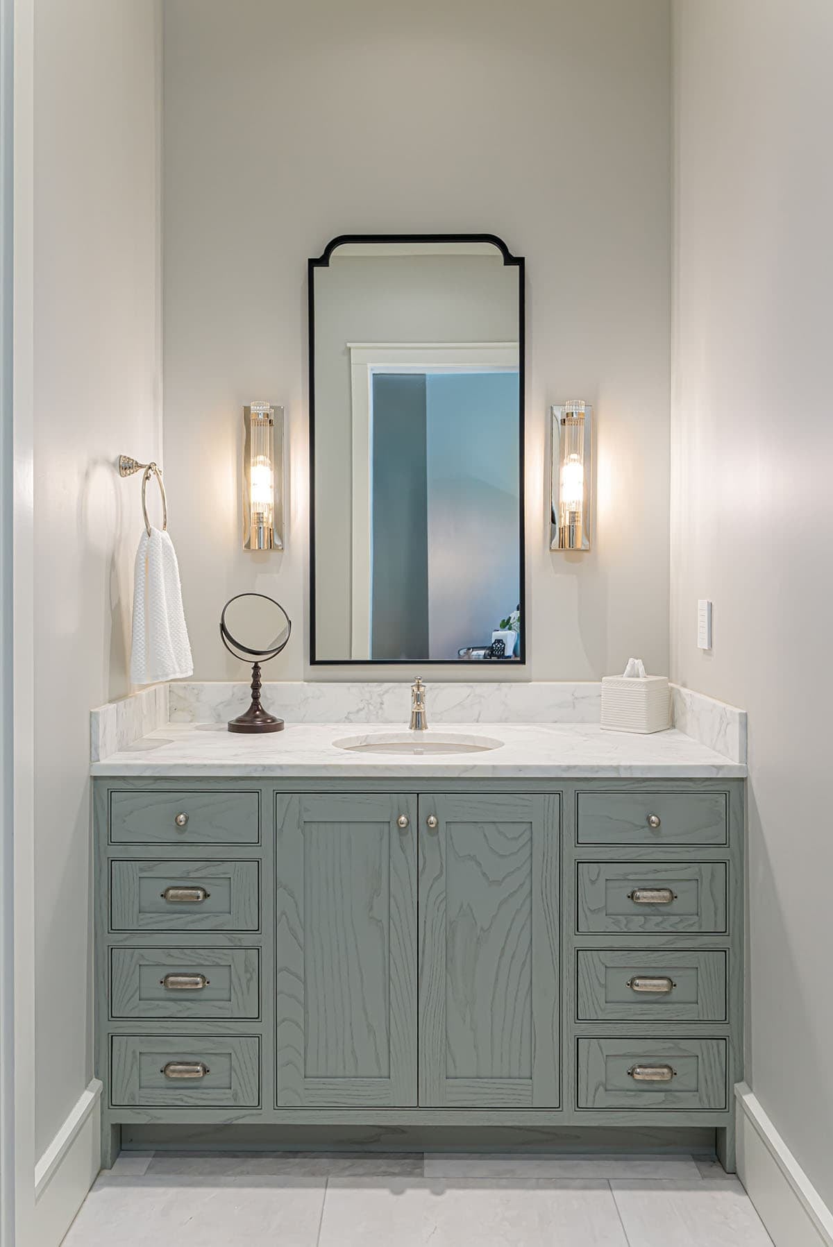Bathroom vanity with sage cabinetry and marble countertop