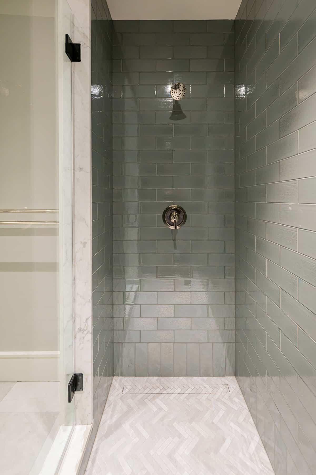 Walk-in shower with blue subway tile and herringbone floor