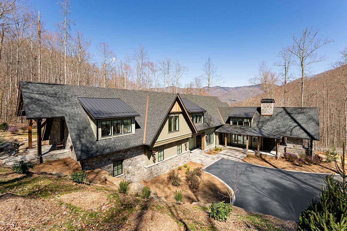 Aerial view of mountain home with curved driveway and forest backdrop