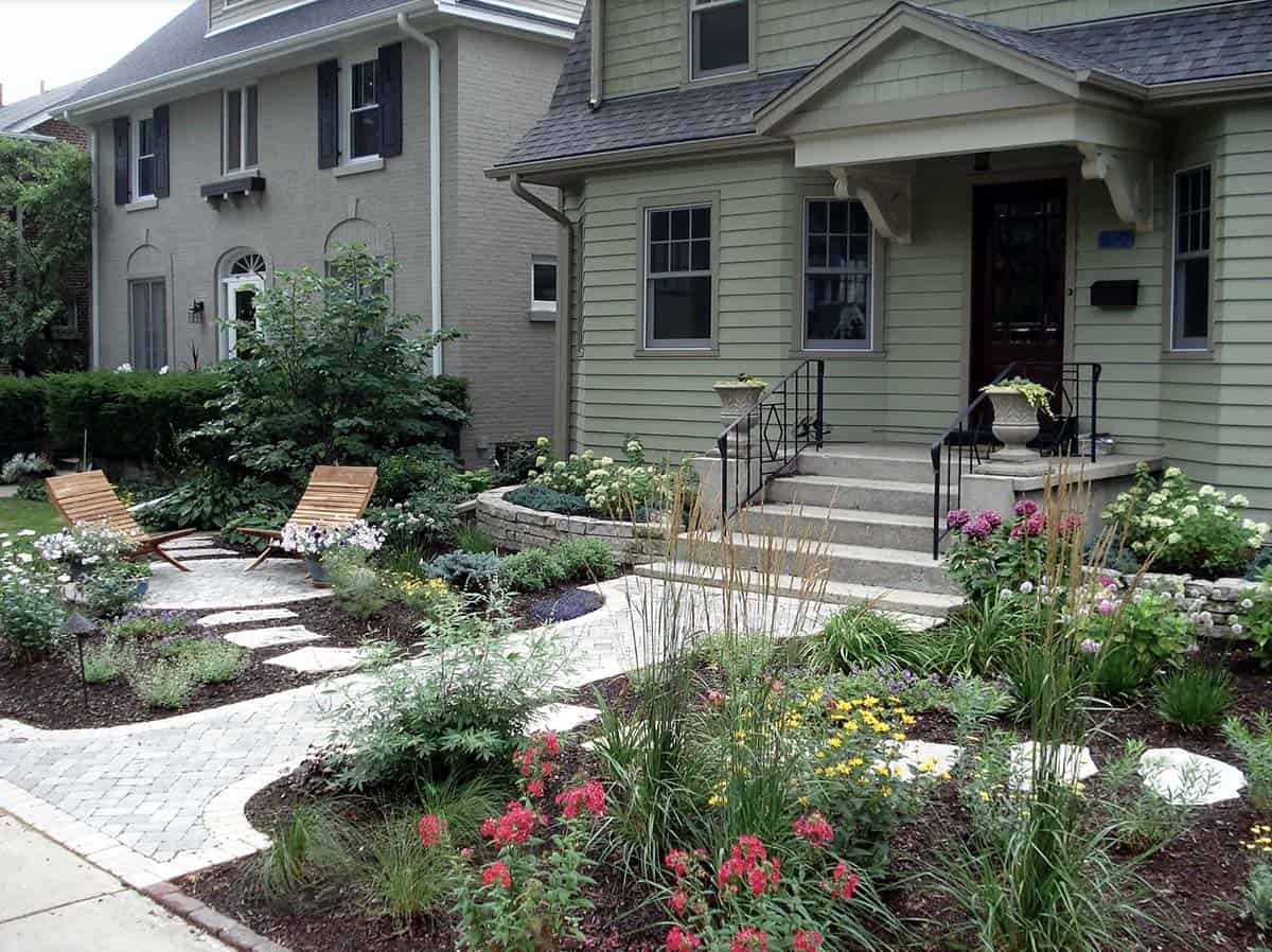 Small front garden with paver walkway, mixed perennial flower beds, and built-in seating area