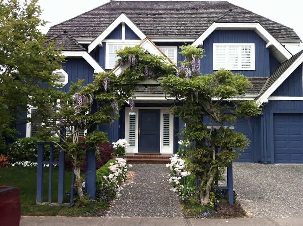 Small front garden with a wisteria-covered arbor framing the entry path