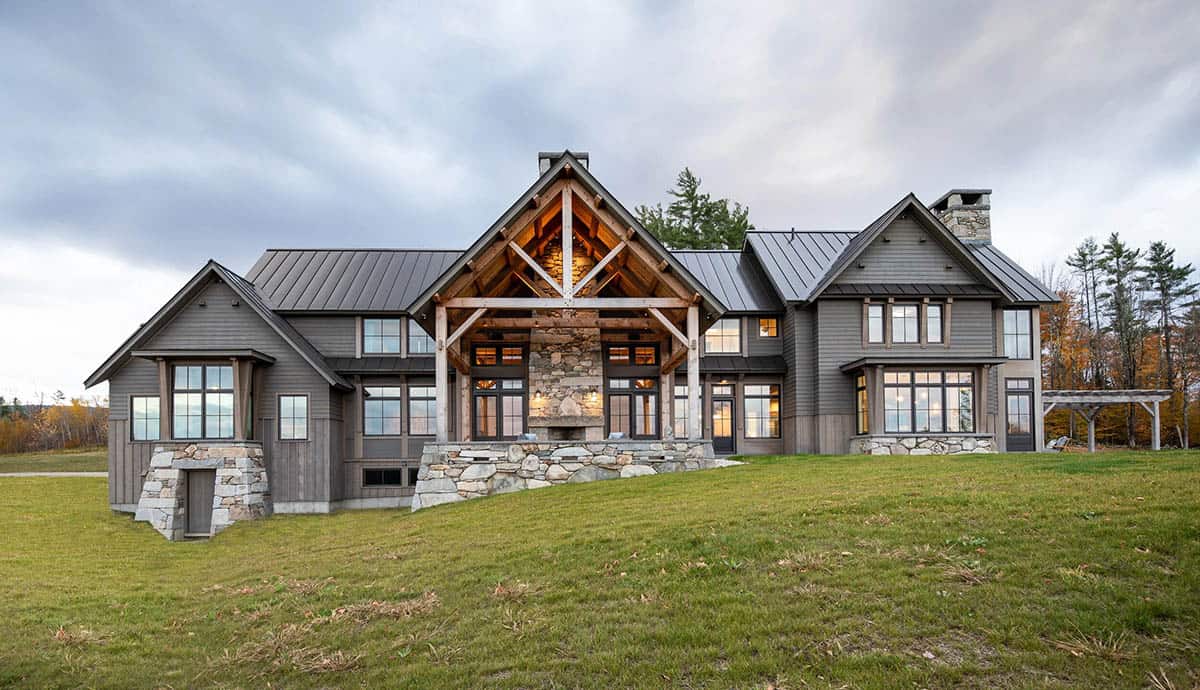 Rear exterior of timber-frame home with exposed gable trusses and stone base
