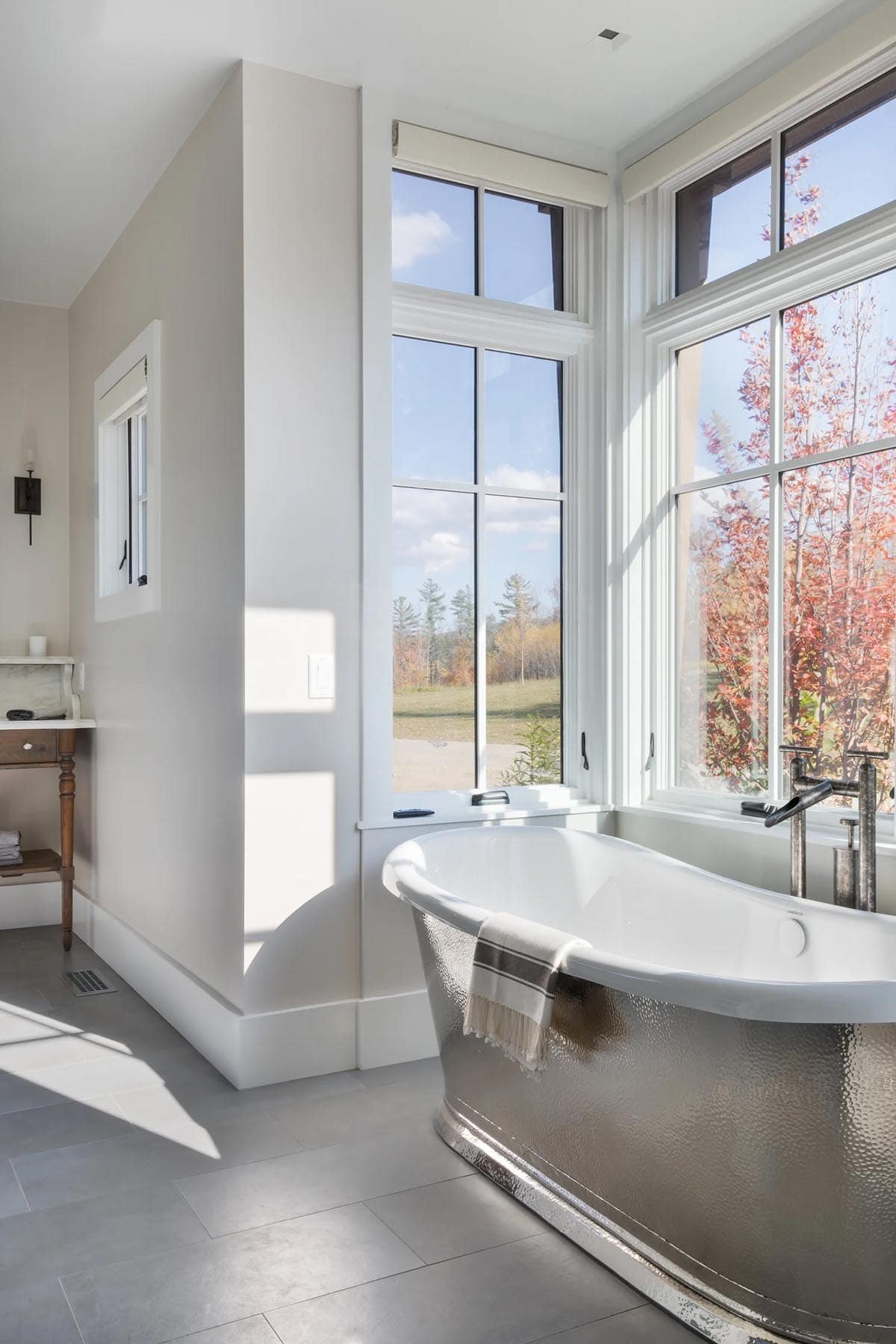 Bathroom with hammered metal soaking tub beneath corner windows