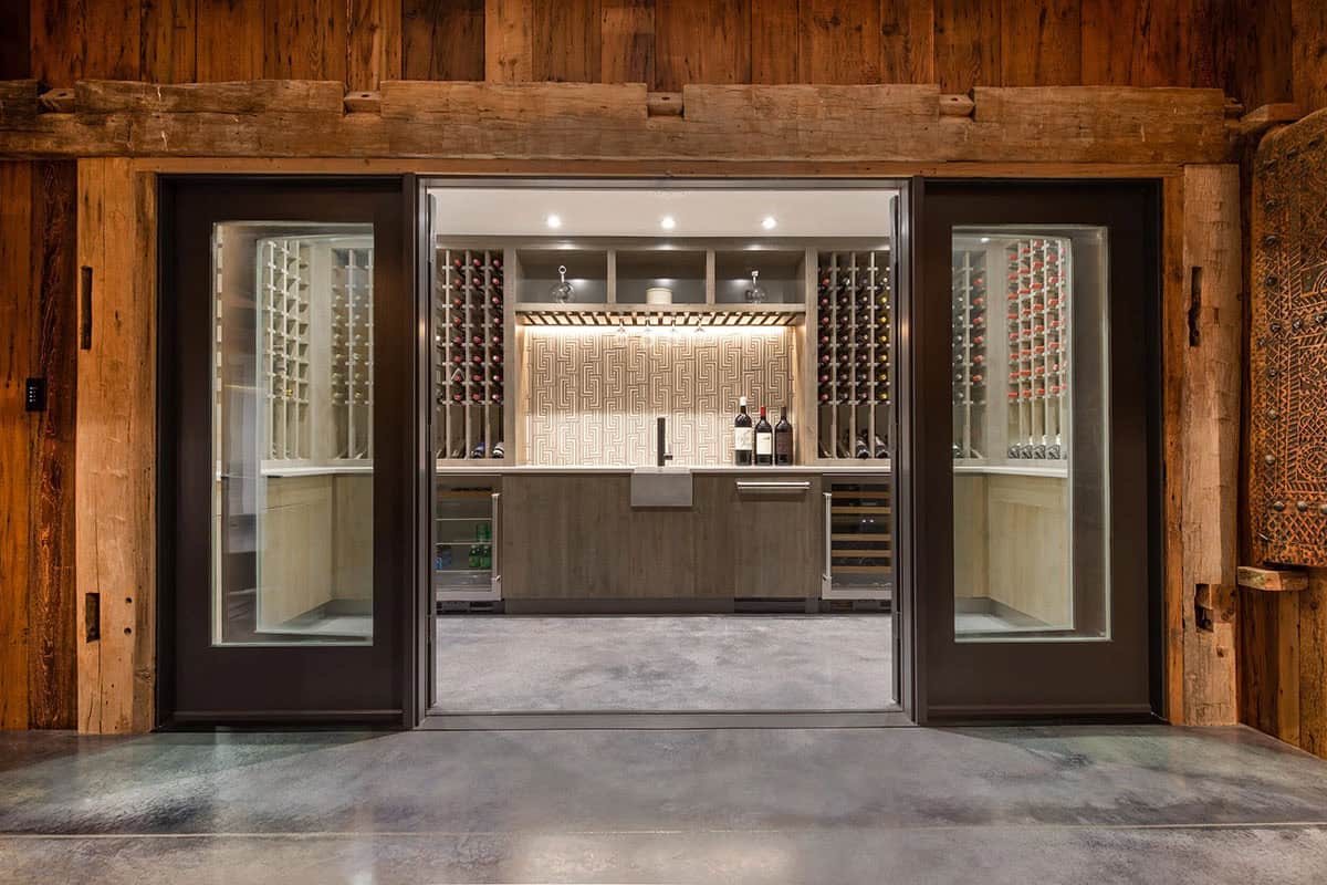 Glass doors opening into a wine cellar with custom storage