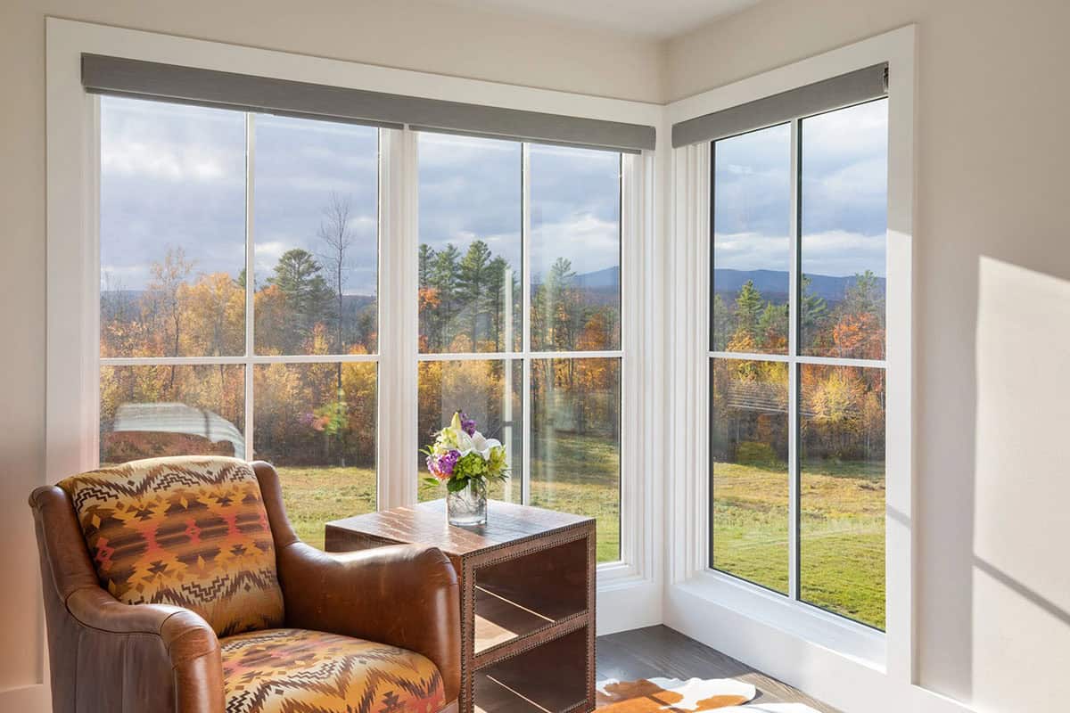 Reading nook with leather armchair and corner windows overlooking fall foliage
