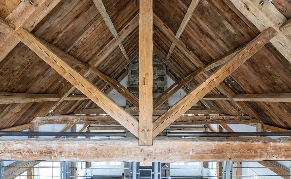 Close-up of timber-frame trusses meeting at a stone chimney