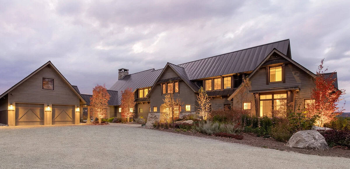 Twilight exterior of timber-frame home with attached garage and stone accents