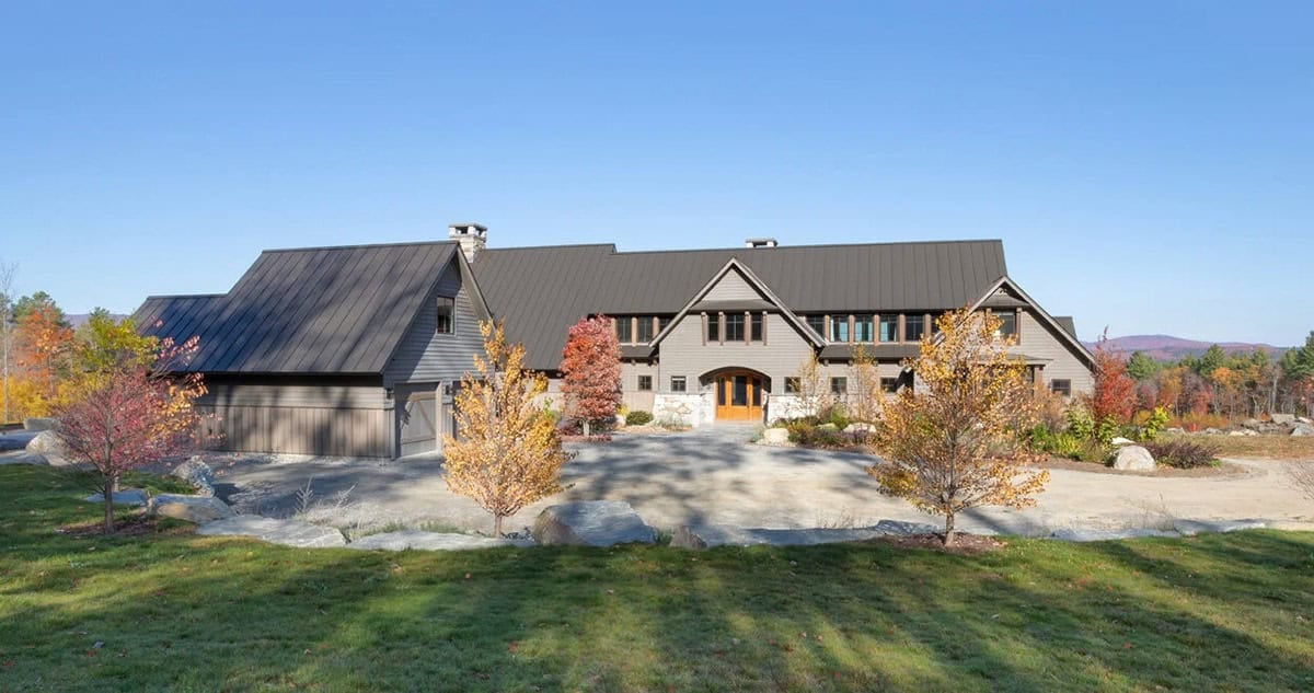 Front exterior of timber-frame home with arched wood door and stone accents