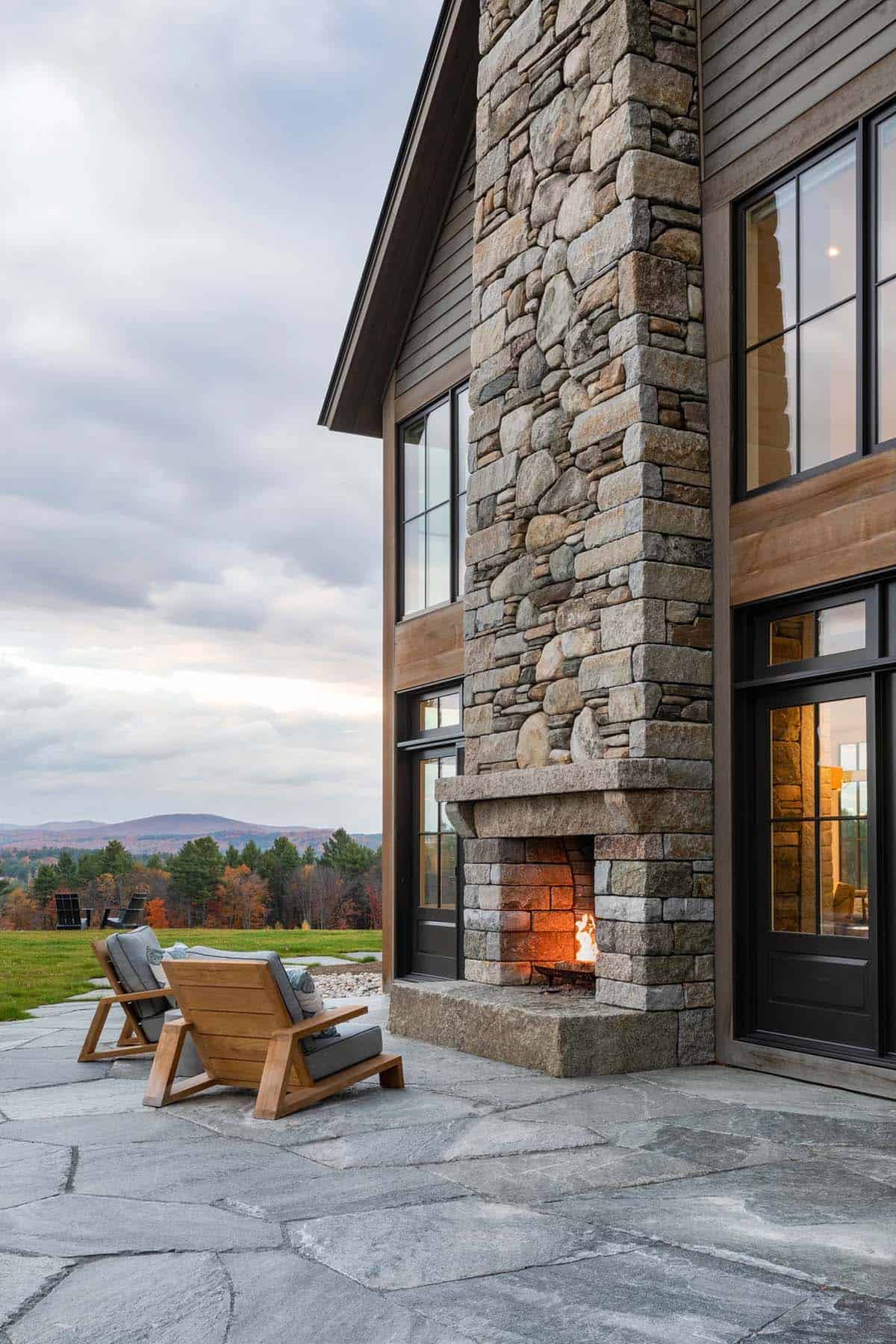 Outdoor stone fireplace on patio with timber-frame home and mountain view