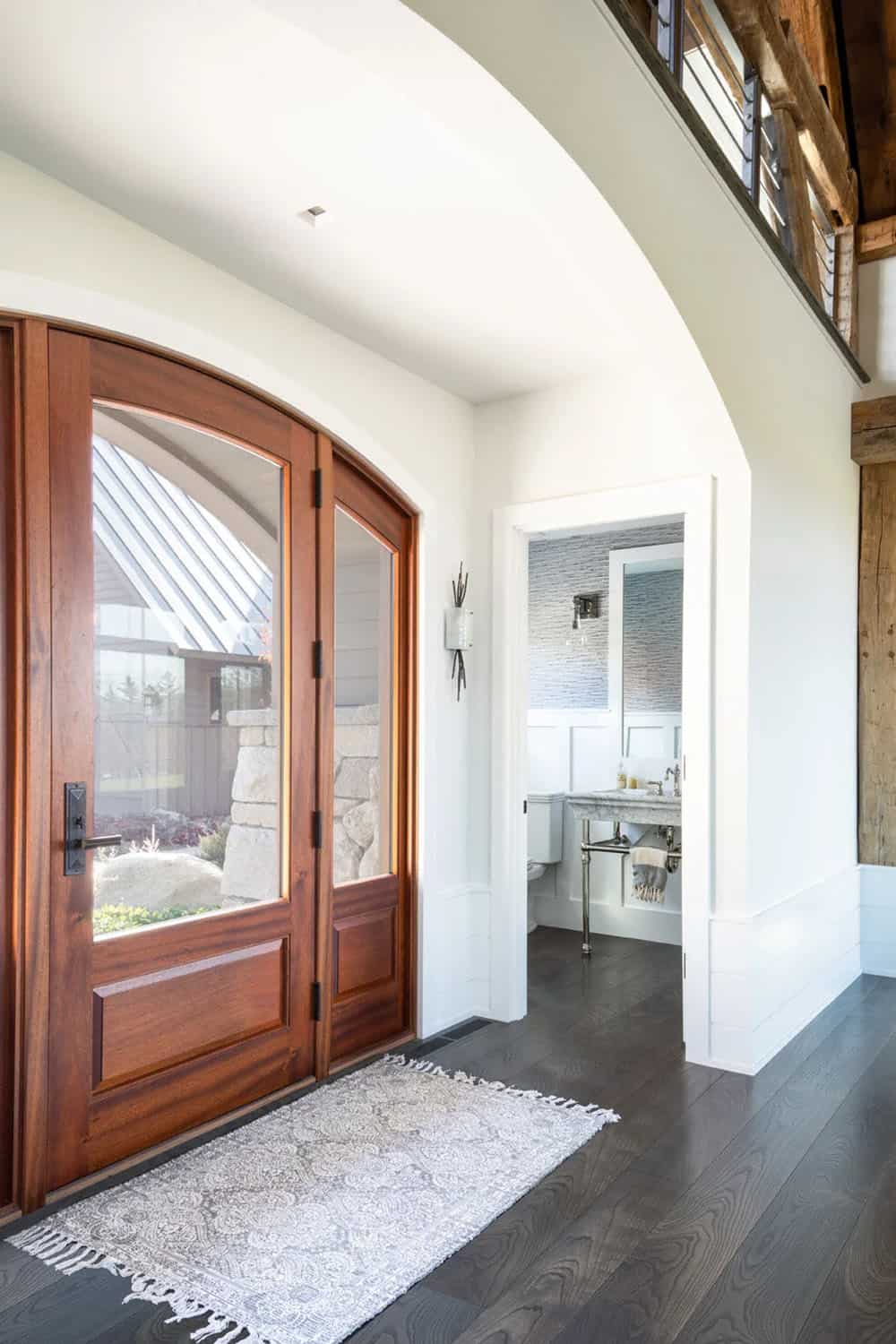 Arched front door entry with view into powder room and loft beams above