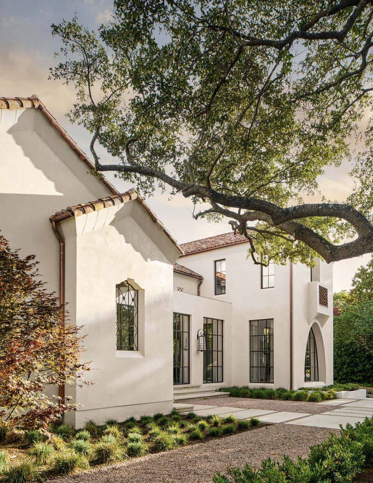 Spanish Colonial Revival home in Texas with arched leaded glass window under oak tree