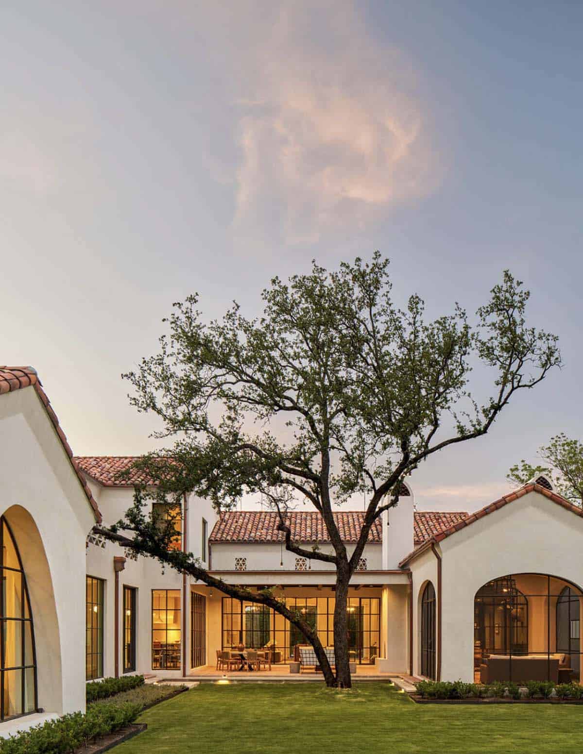 Spanish Colonial Revival home in Texas courtyard with mature oak tree at dusk