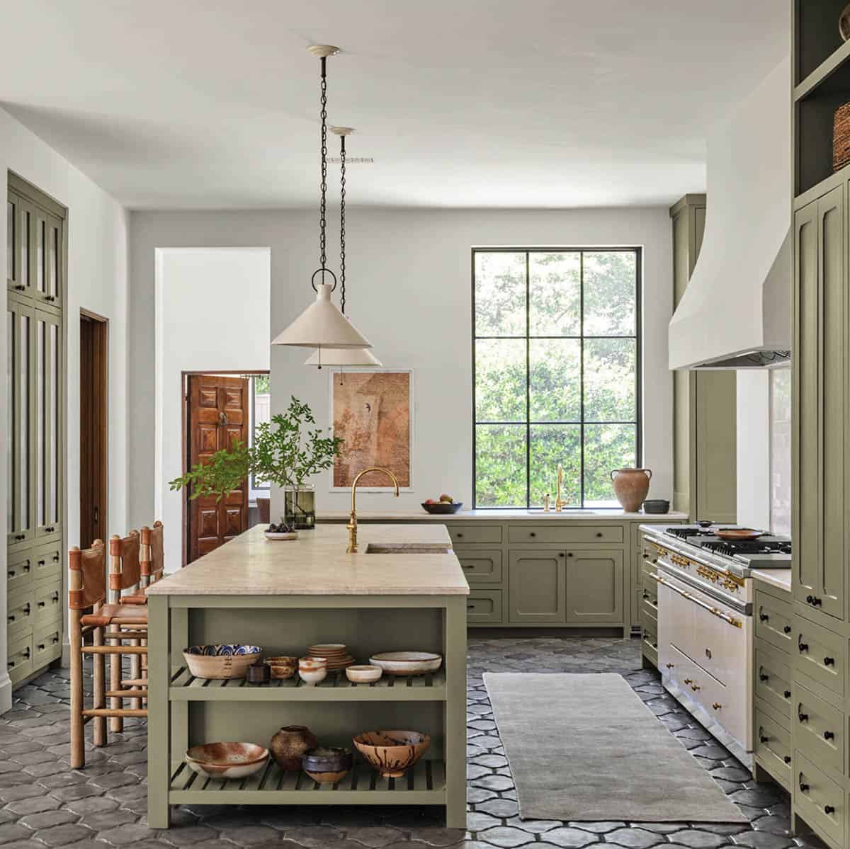 Sage green kitchen with marble island and Spanish tile floor in Texas home