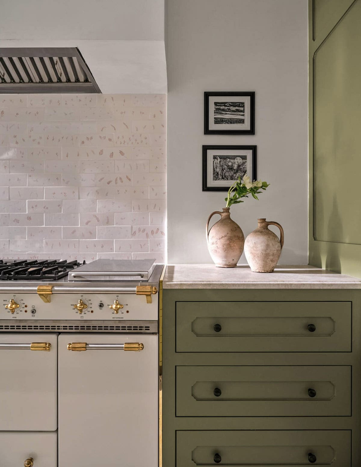 Kitchen detail with brass range hardware and stoneware vases on marble counter