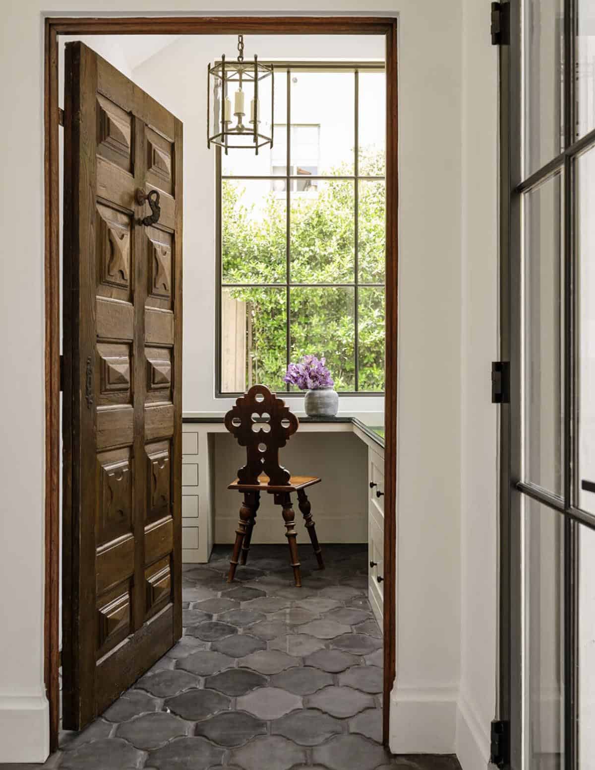 Antique carved wood door opening to built-in desk nook with steel window