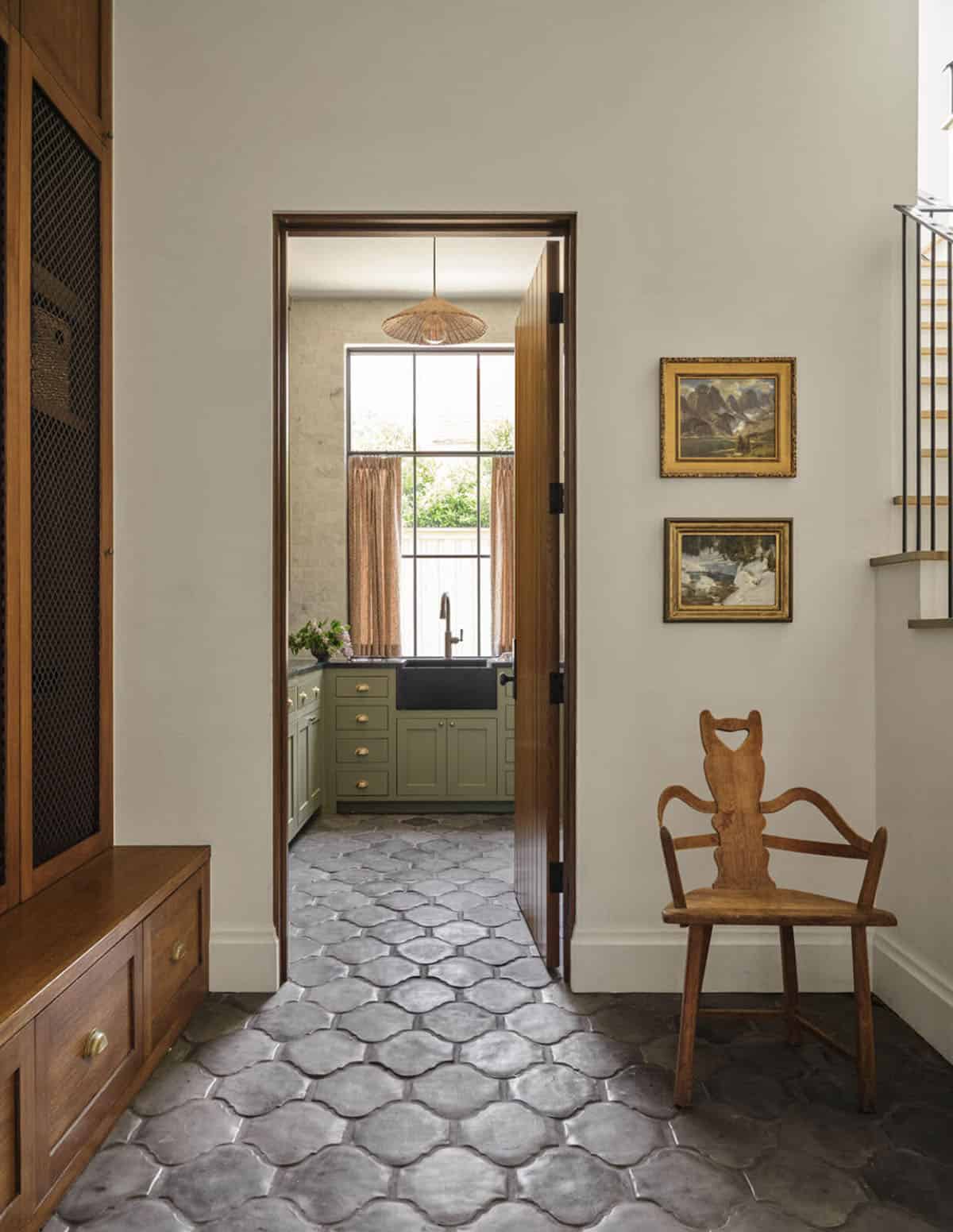 Hallway with vintage gilt-framed art leading to sage green butler's pantry