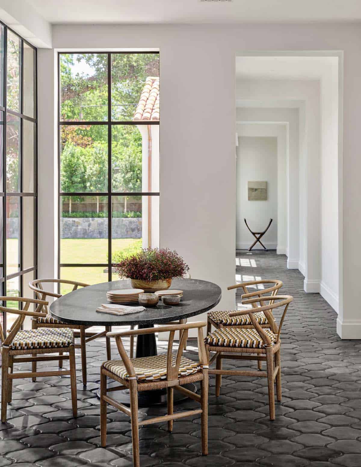 Breakfast nook with round table and wishbone chairs beside steel window wall
