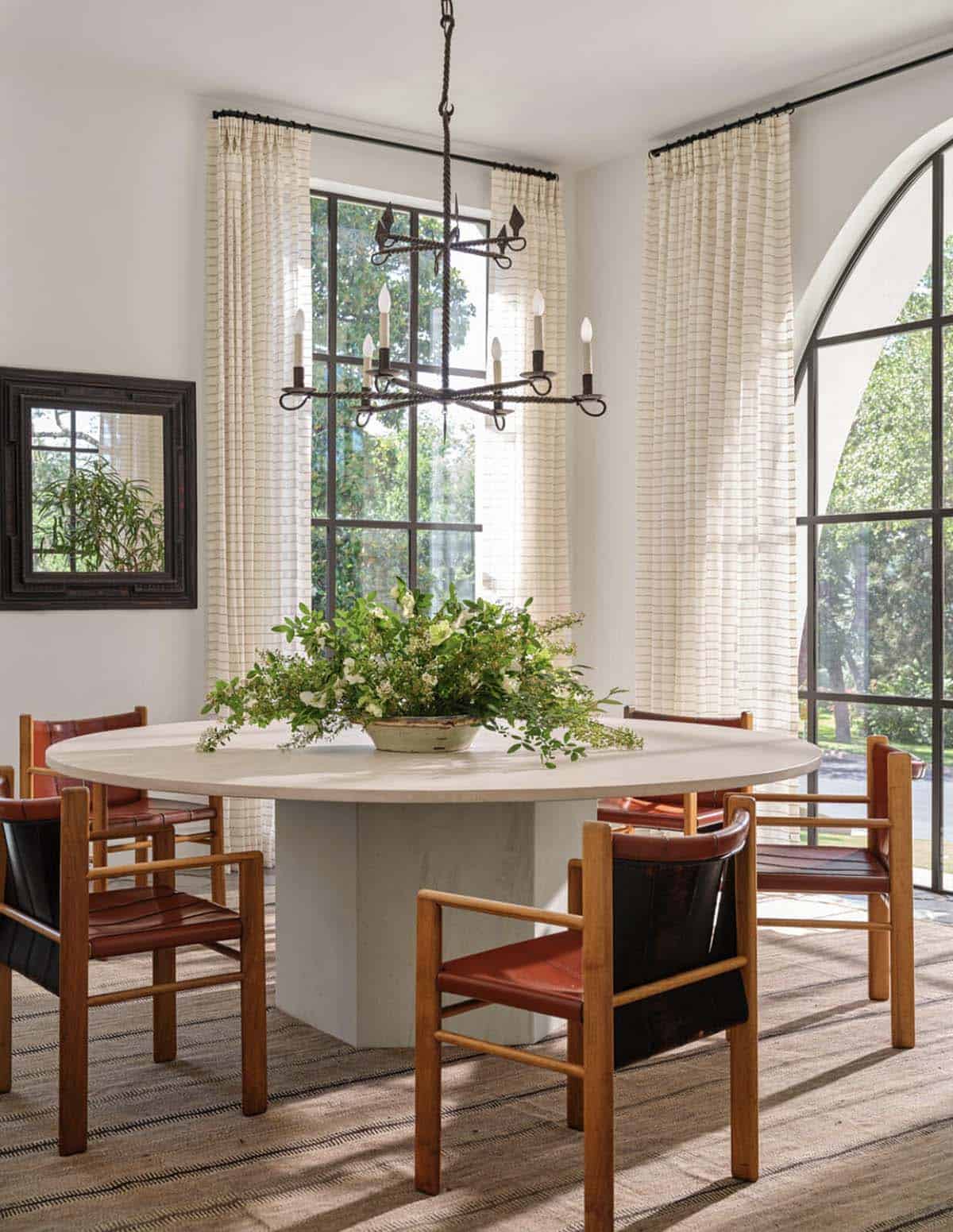 Round dining table with leather chairs and wrought iron chandelier in Spanish Colonial home