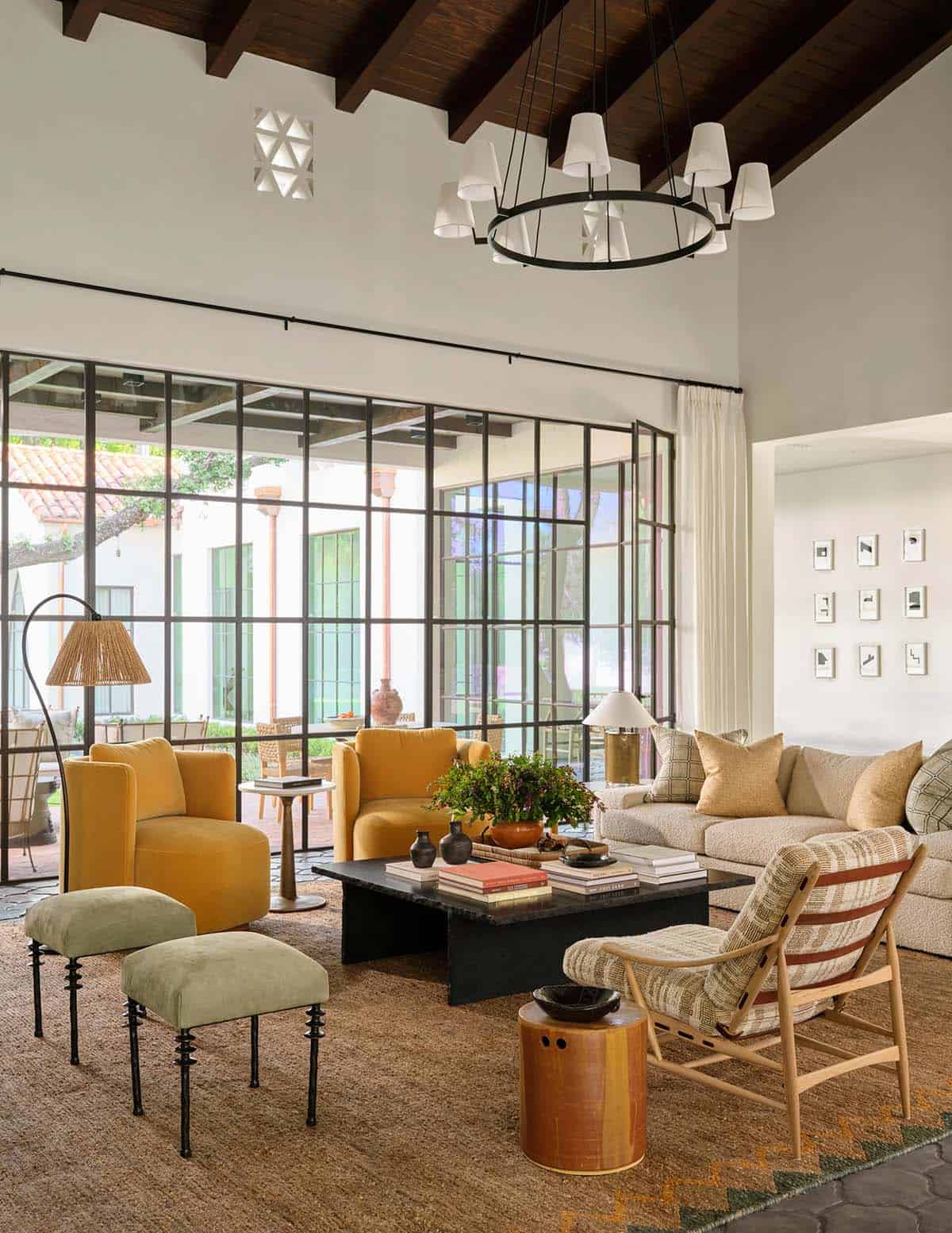 Living room with steel glass wall opening to courtyard and mustard velvet chairs