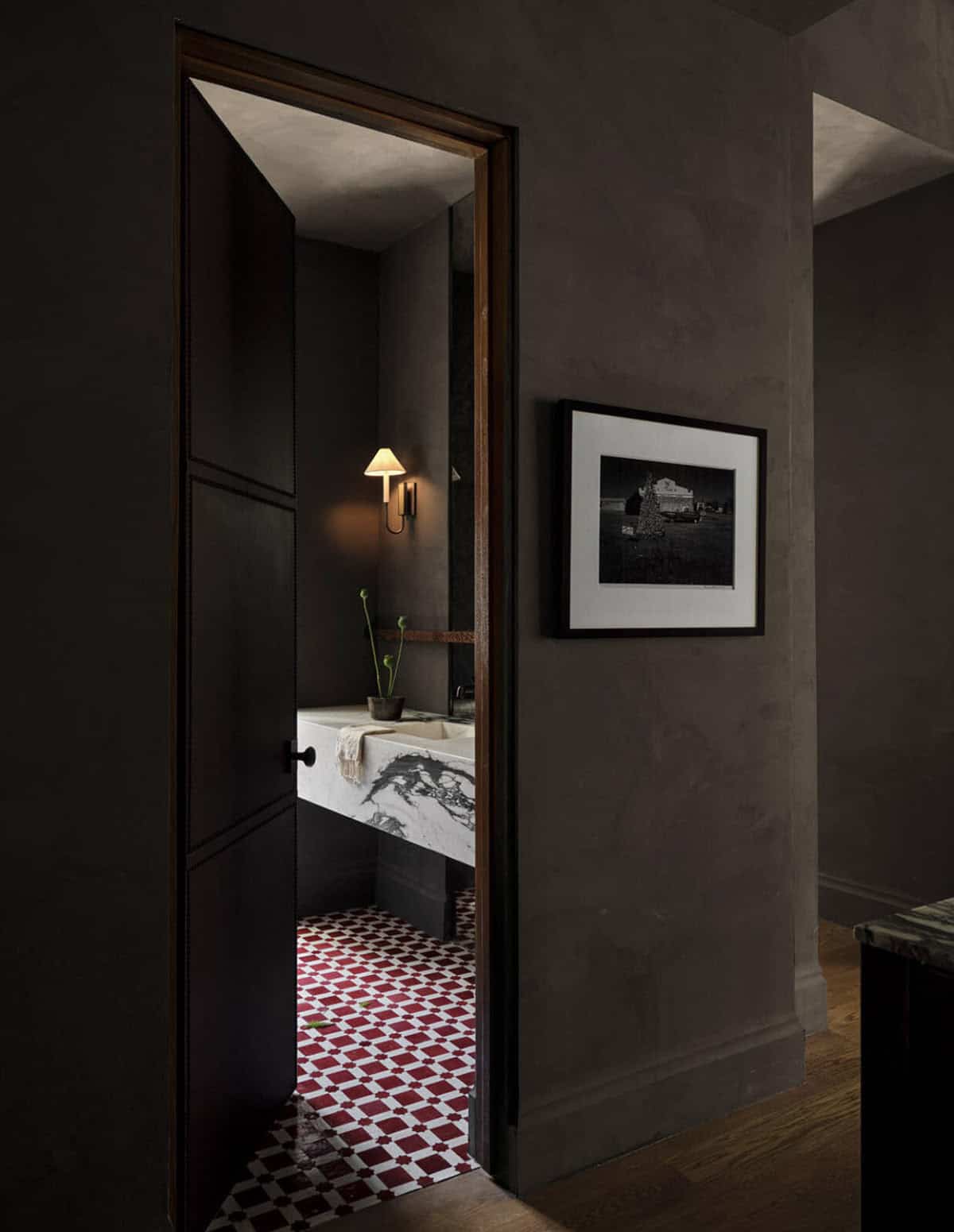 Dark powder bathroom with marble sink and red patterned tile floor