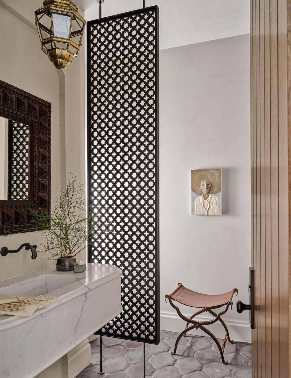 Powder room with carved wood screen divider and marble trough sink