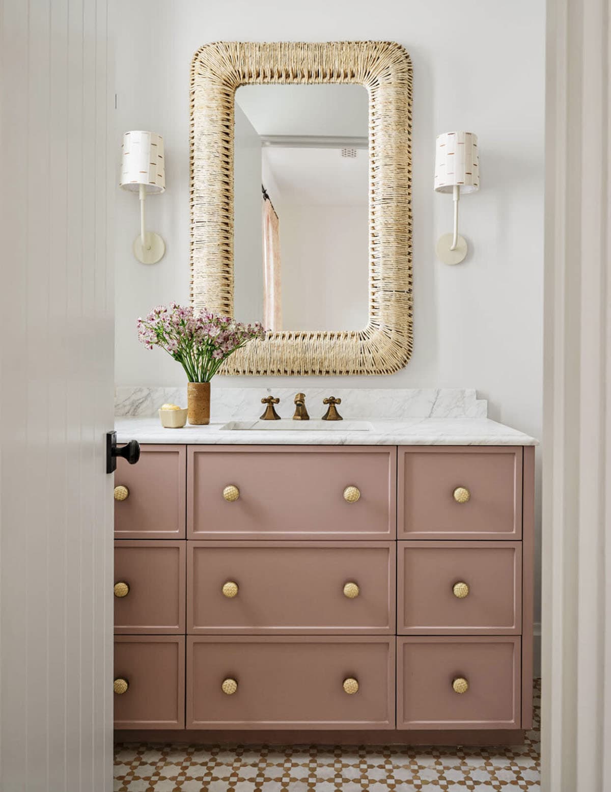 Pink bathroom vanity with woven rattan mirror