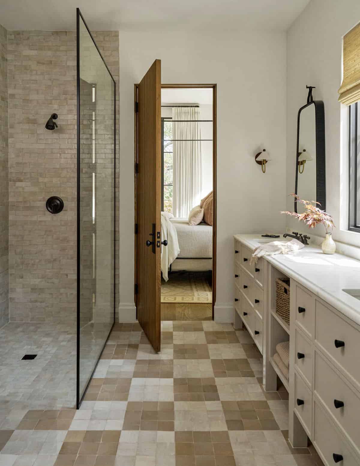Bathroom with checkered tile floor and glass shower opening to bedroom