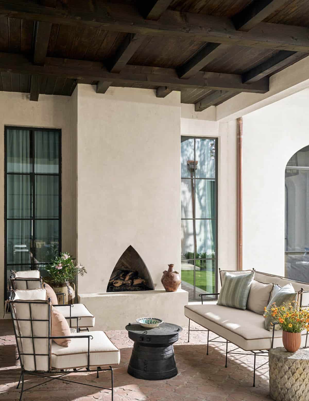 Outdoor living area with arched fireplace and iron lounge chairs