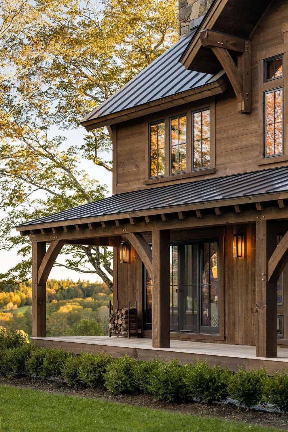 Covered porch with timber posts, black metal roof, and firewood rack at dusk