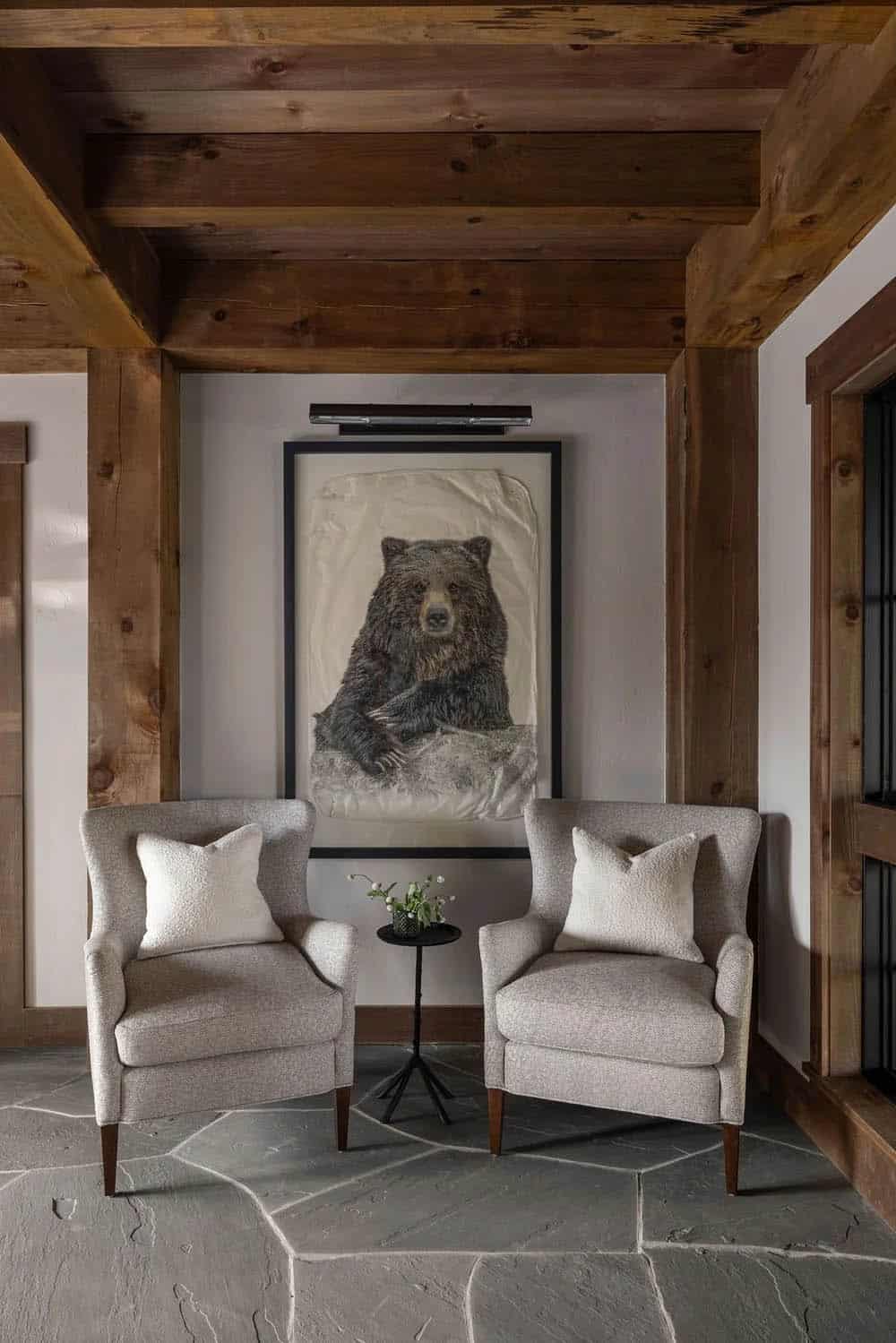 Reading nook with two upholstered armchairs beneath a framed bear artwork