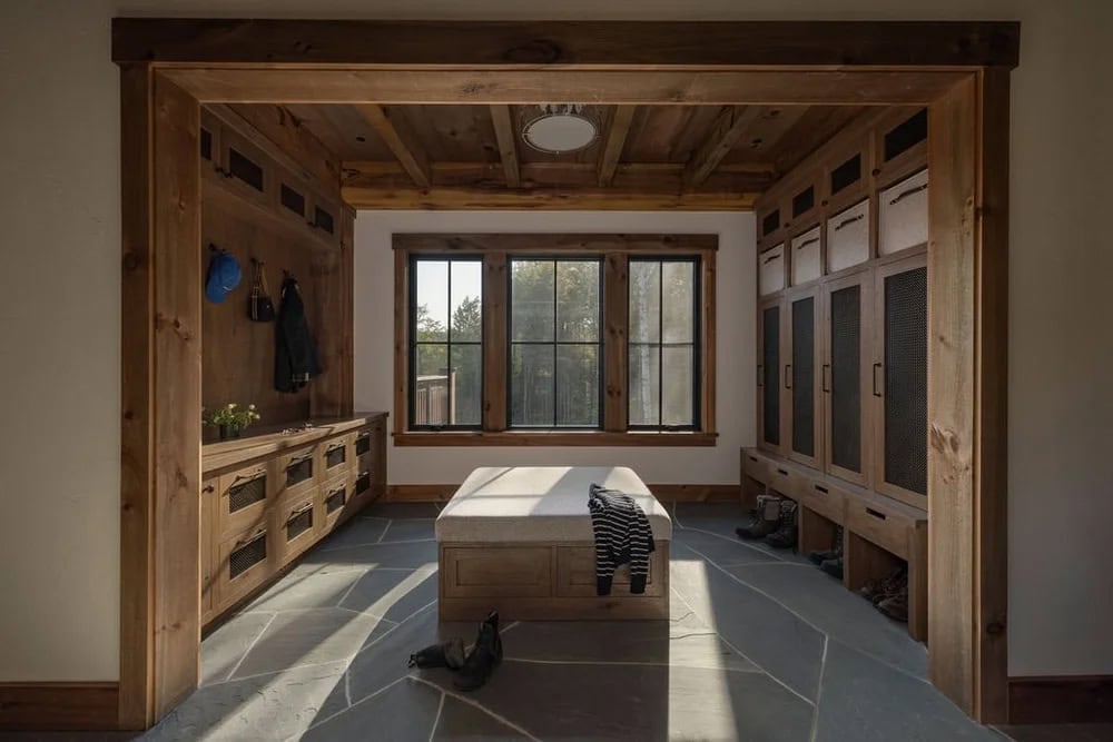 Mudroom with built-in wood lockers, bench seating, and stone tile floor