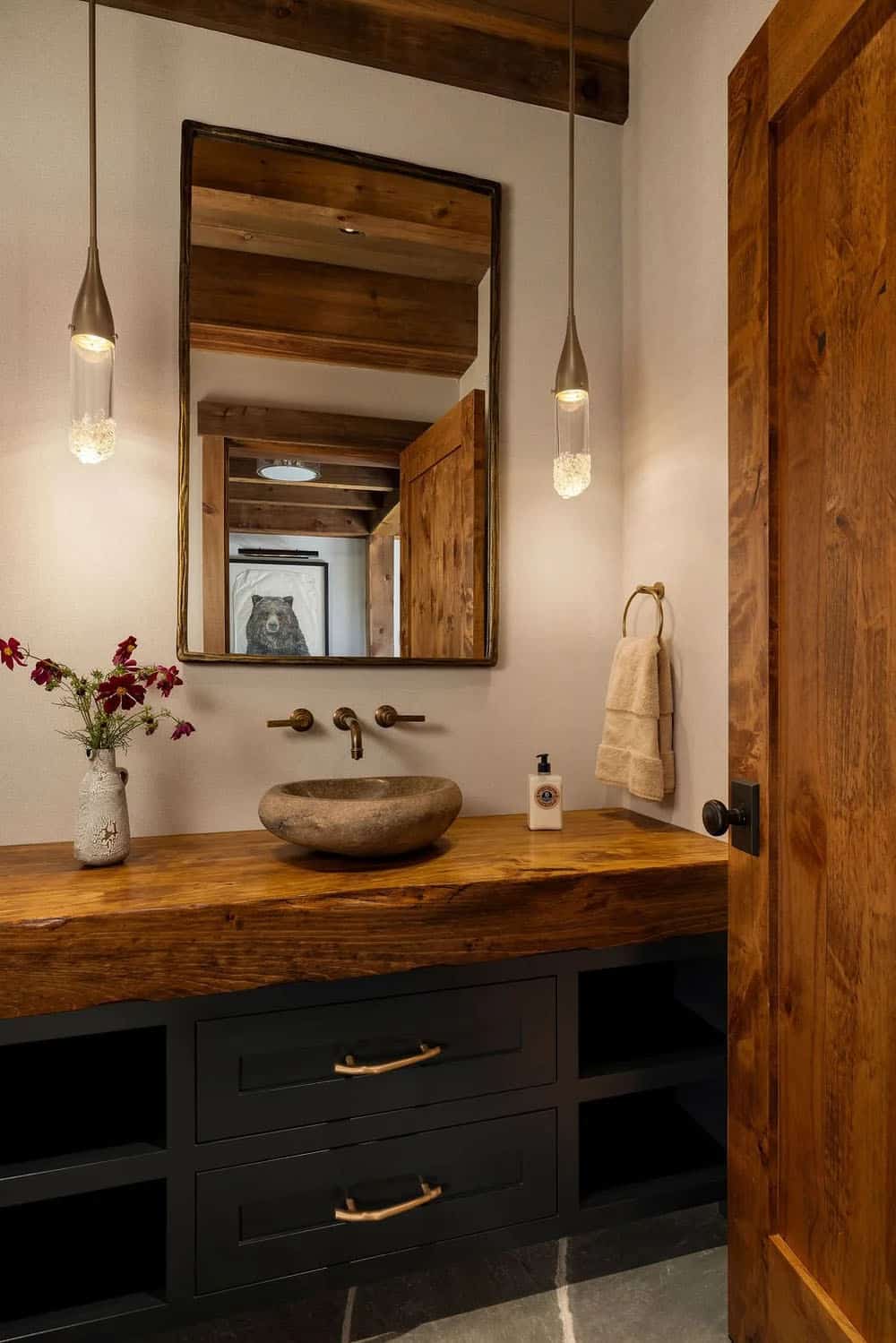 Powder room with stone vessel sink, wood countertop, and pendant lighting