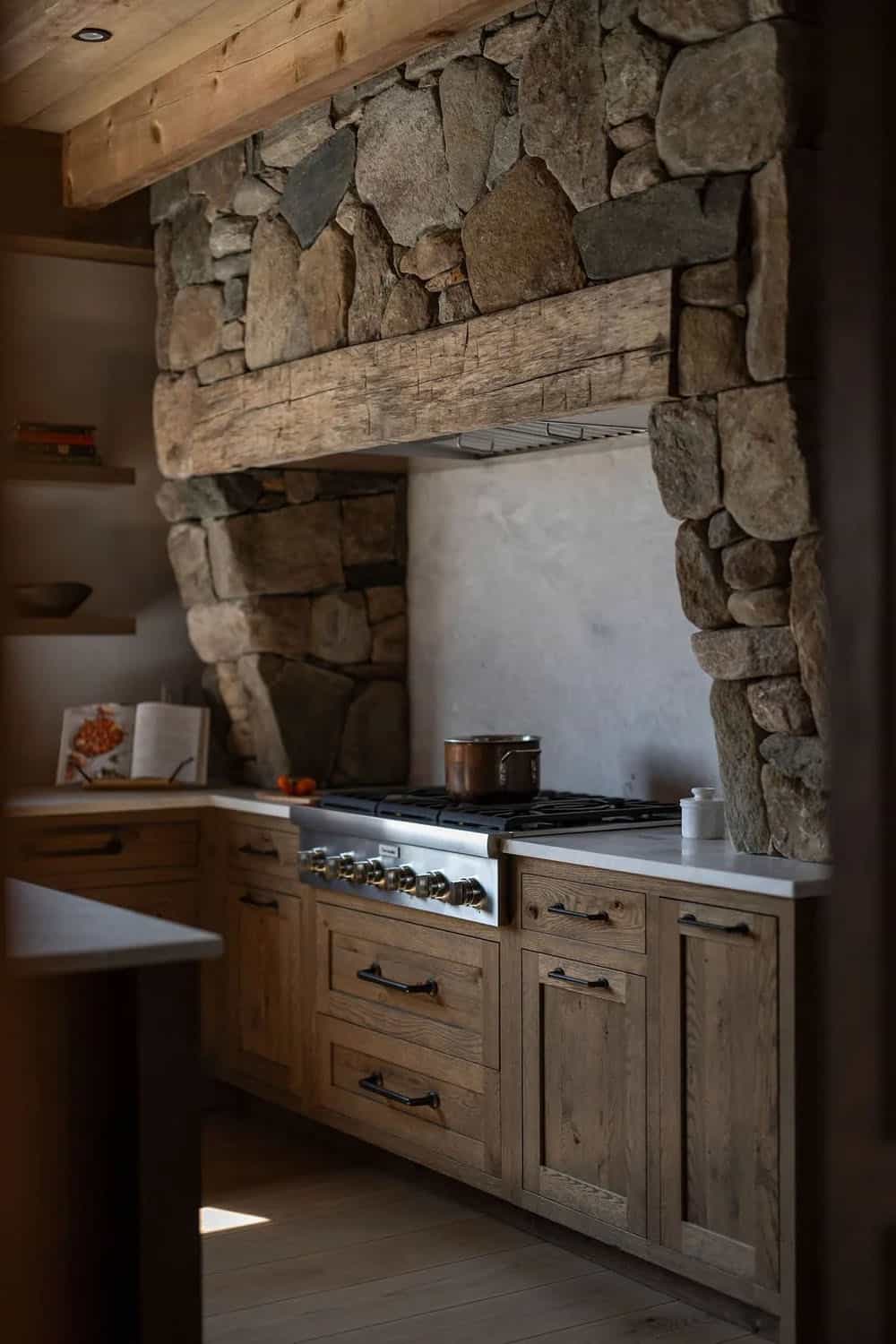 Stone hood range surround over gas stove with wood cabinetry