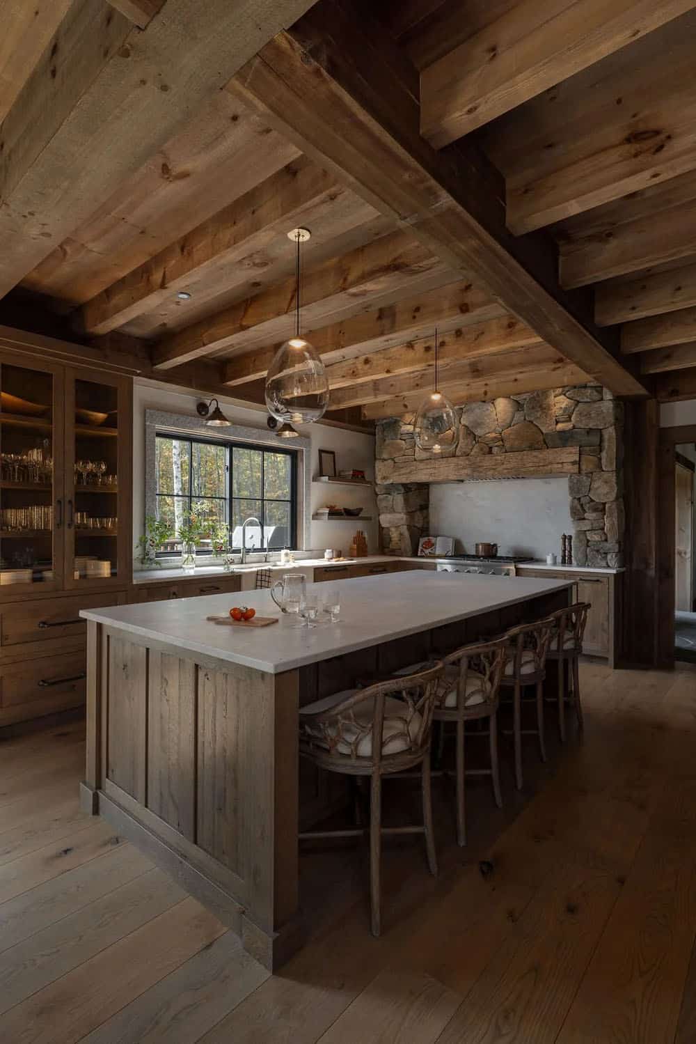 Kitchen island with bar stools beneath wood beam ceiling and pendant lights