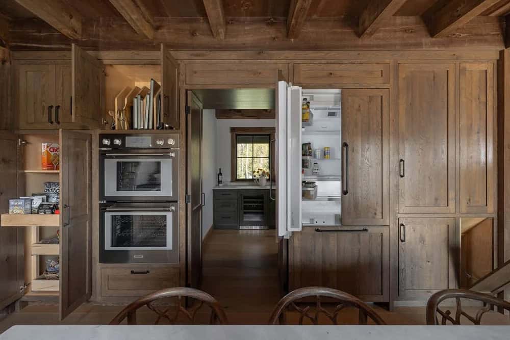 Kitchen wall of cabinetry with open refrigerator and pantry storage