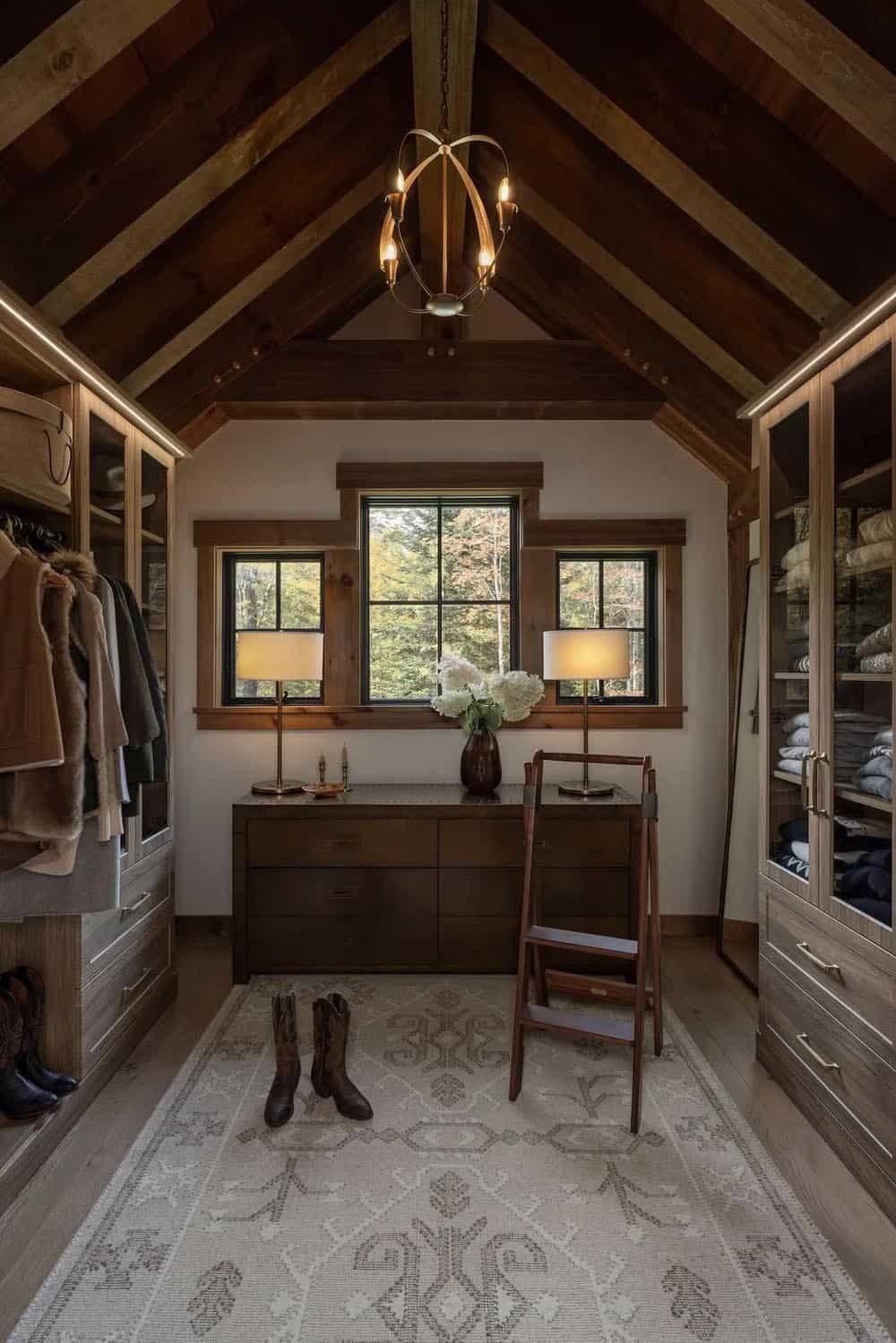 Walk-in closet with vaulted ceiling, antler chandelier, and dresser between windows