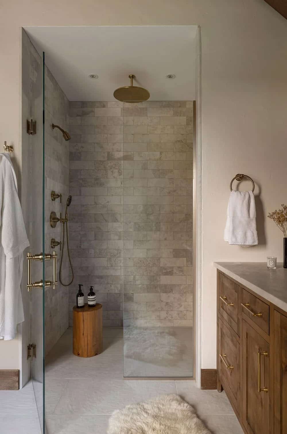Walk-in shower with subway tile, brass rain showerhead, and glass door