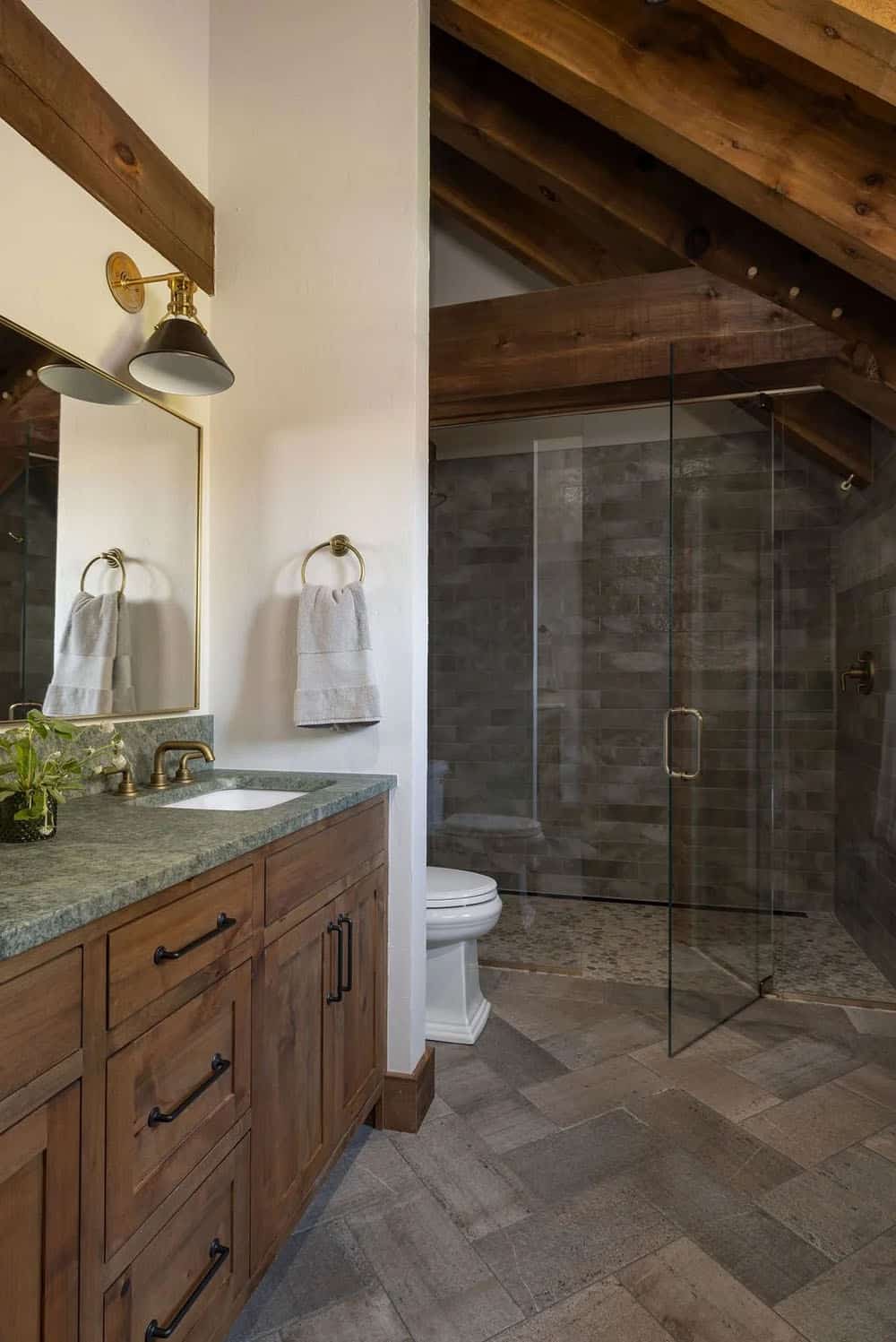 Bathroom with green stone countertop, dark hardware, and glass shower enclosure