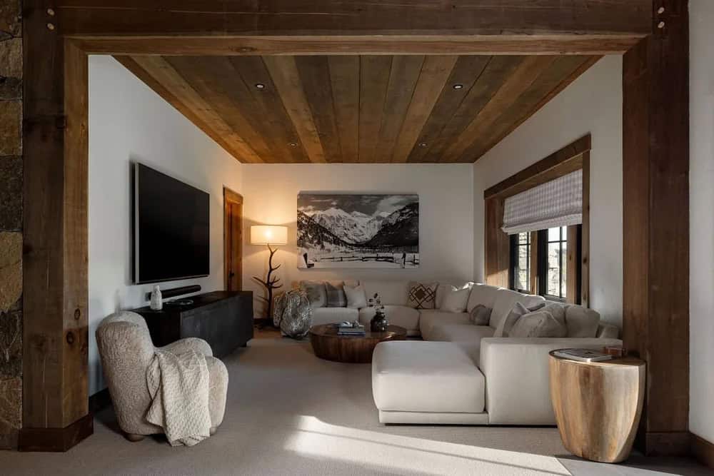 Den with sectional sofa, mounted TV, and black-and-white mountain artwork
