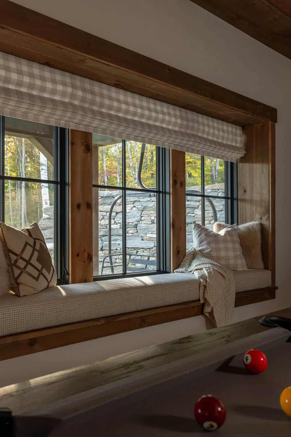 Window seat with plaid cushions overlooking stone wall and ski lift chair