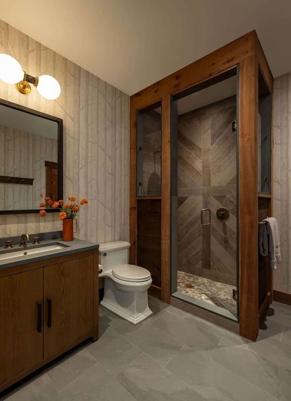 Bathroom with birch-print wallpaper, wood vanity, and chevron-tiled shower