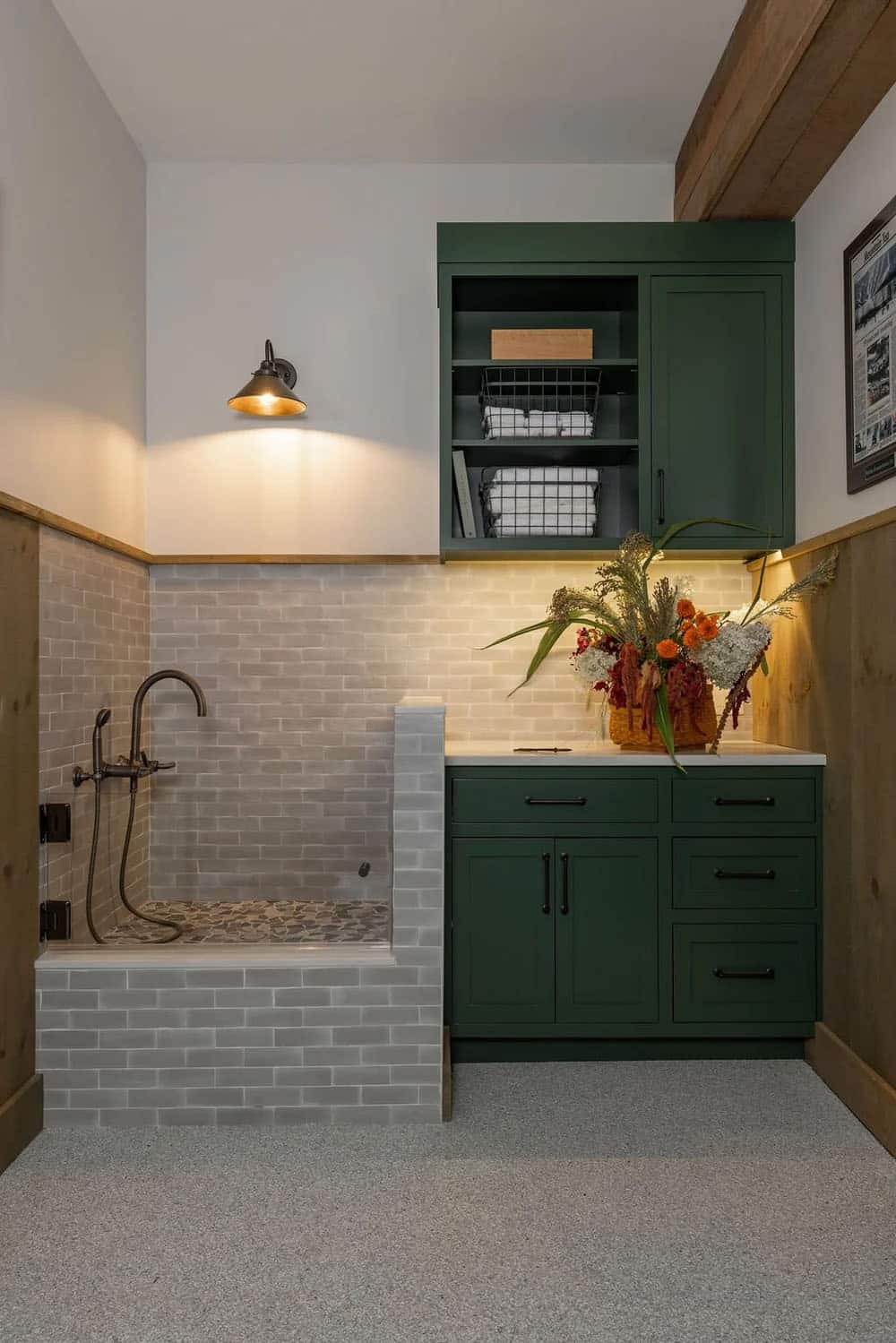 Dog wash station with tiled surround beside green mudroom cabinetry
