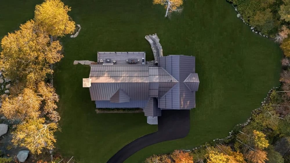 Aerial view of timber frame home's metal roofline surrounded by fall foliage